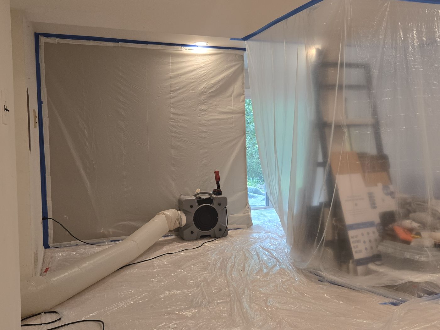 Plastic containment and an air scrubber set up inside a home during mold remediation